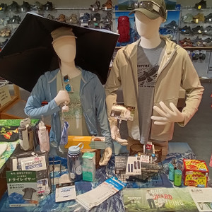 Kimg20260713_120441421 登山用品店の売場で、マネキン2体による夏の登山コーディネートと、晴雨兼用傘、ドライレイヤー、防虫用品などの関連アイテムを展示