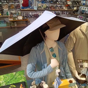 Kimg20260713_121157760 登山用品店で、遮熱・遮光タイプの折り畳み傘を持ったマネキンが夏のアウトドアコーディネートを紹介している様子