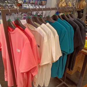 ピンク、ベージュ、ホワイト、ブルー、ブラックのノースフェイス吸汗速乾機能付き半袖Tシャツがハンガーラックに並ぶ店頭ディスプレイ